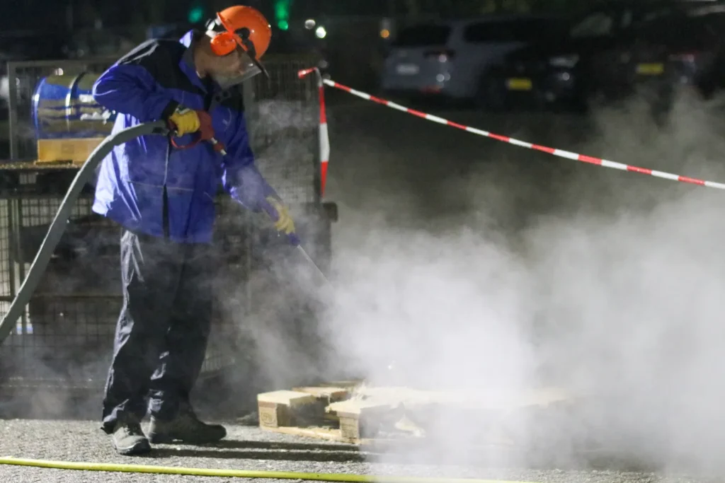 Arbeiter mit Hochdruck-Wasserstrahlgerät in Schutzkleidung