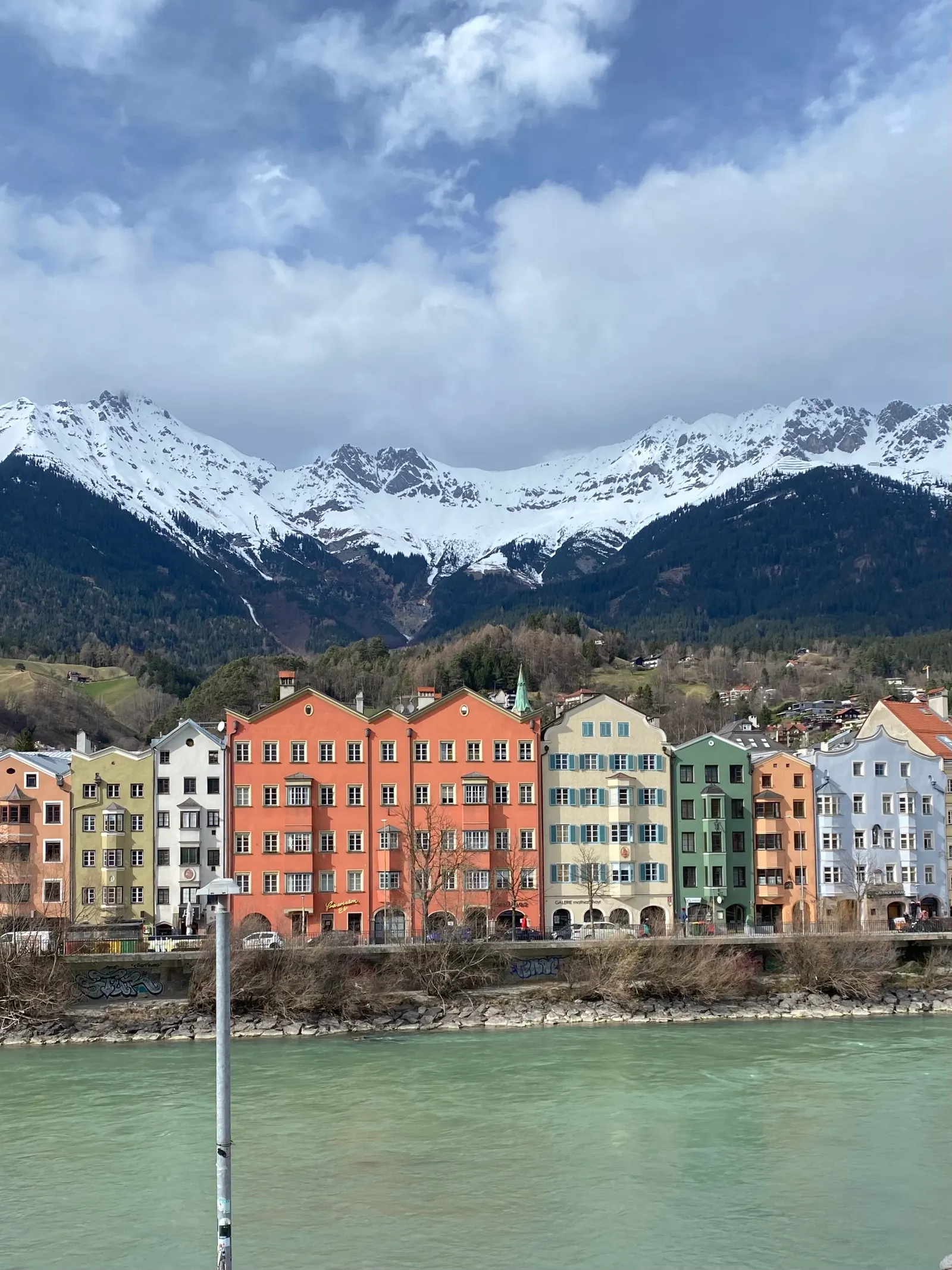 Bunte Häuser am Inn vor verschneiten Bergen in Innsbruck